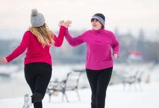 Two women high-fiving while outdoors in snow