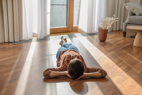 Person lying on their back on the floor in front of a glass door with sunlight coming in